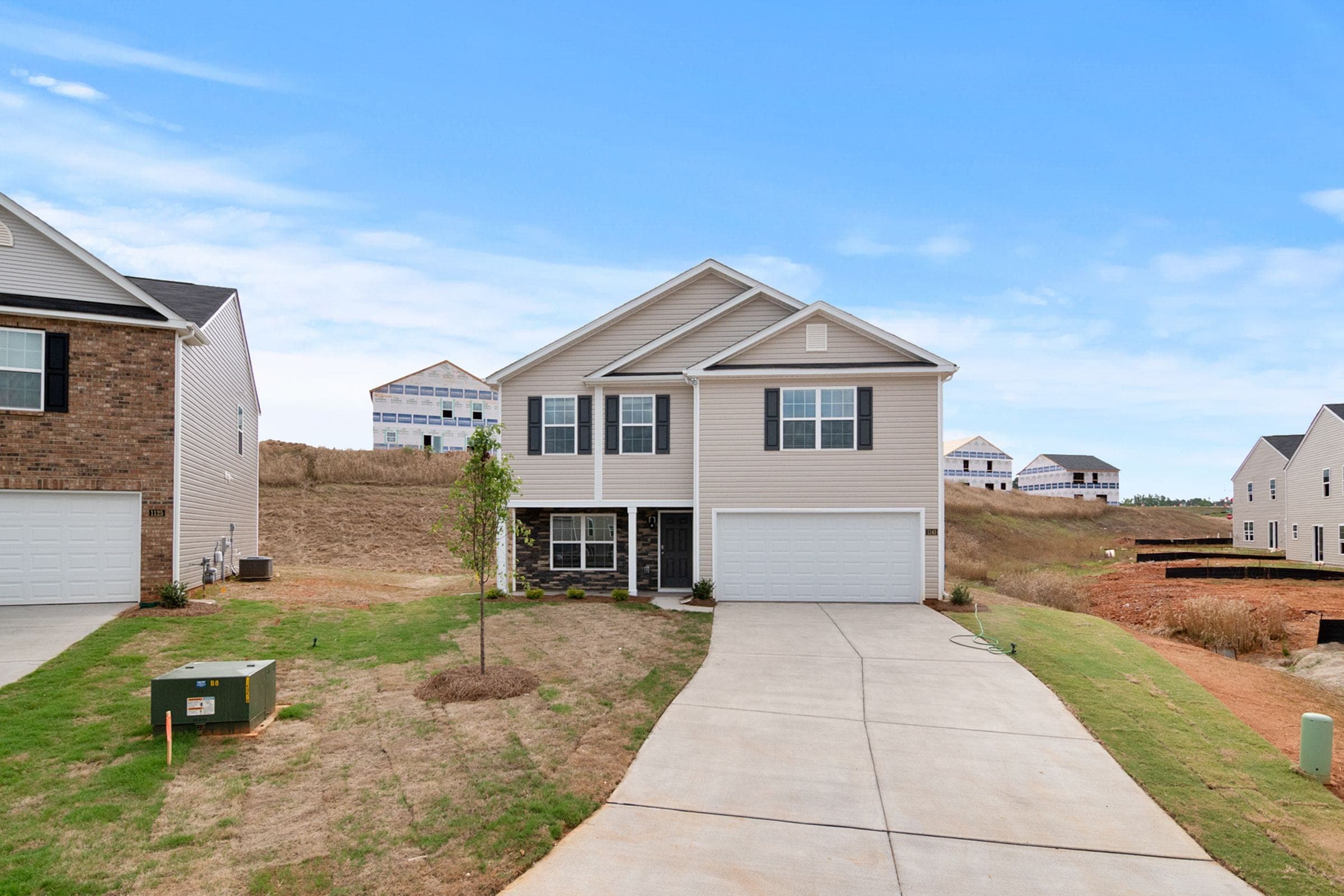 Junk removal in Karns, TN: new two-story vinyl-sided house with a young tree, fresh lawn and more homes going up behind
