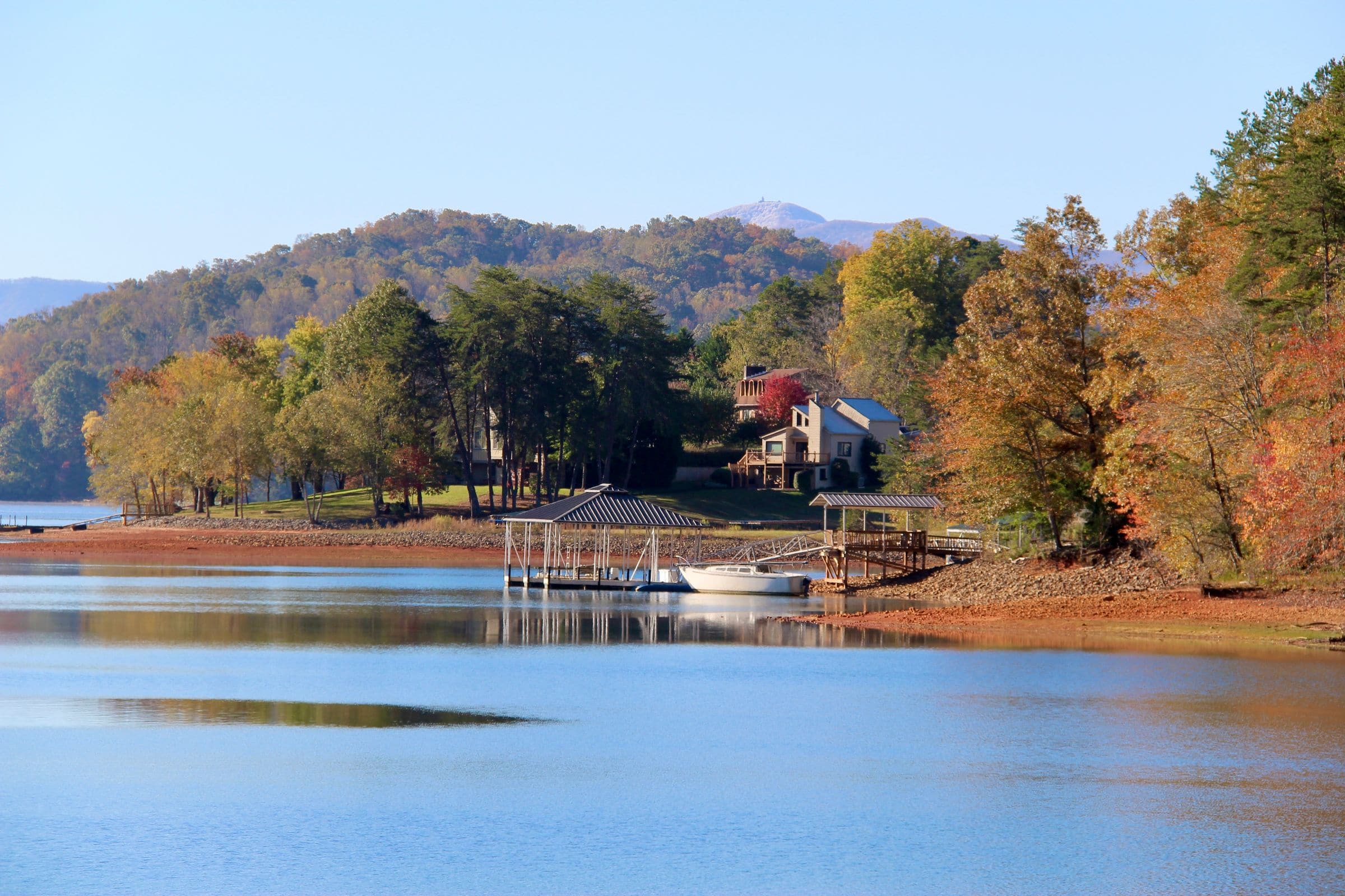 Junk removal in Lenoir City, TN: lake houses with covered boat docks on a wooded shoreline with hills behind in fall